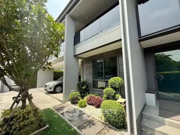 Modern two-story house with landscaped garden and carport in a serene neighborhood.