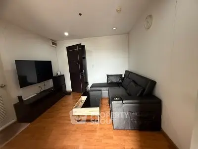 Modern living room with sleek black furniture and wall-mounted TV, perfect for cozy relaxation.