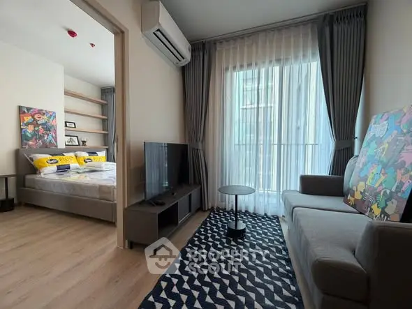 Modern living room with stylish decor and natural light, adjacent to a cozy bedroom.