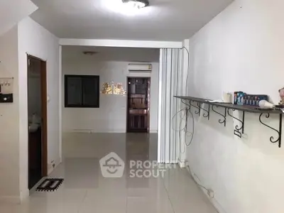 Spacious interior with tiled flooring and wall-mounted shelves, ideal for versatile living space.