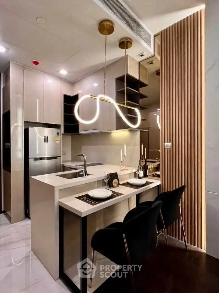 Modern kitchen with sleek design, featuring island seating and contemporary lighting.
