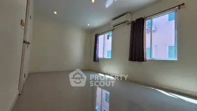 Spacious and well-lit empty room with glossy floor, ready for customization, featuring two windows with dark curtains and a neutral color palette.
