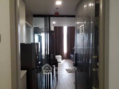 Modern apartment interior showcasing a sleek hallway leading to a cozy living area with ample natural light and contemporary furnishings.