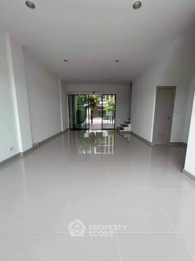 Spacious empty room with glossy tiled floor and large sliding glass doors.