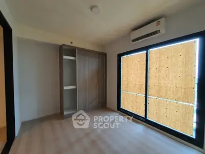 Spacious bedroom with large window and built-in wardrobe, featuring modern air conditioning.