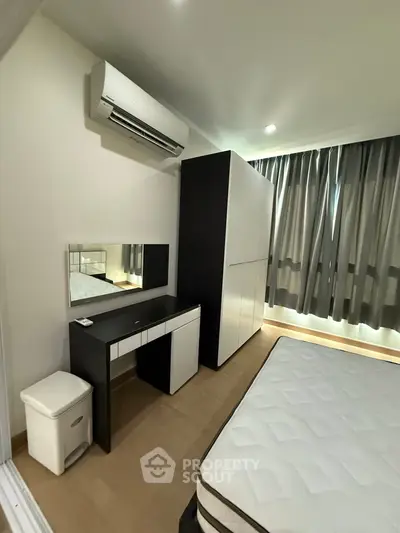 Modern bedroom with sleek furniture and air conditioning, featuring a stylish wardrobe and cozy ambiance.