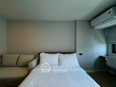 Modern bedroom with cozy bed, sofa, and air conditioning unit