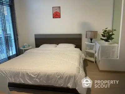 Serene bedroom with a large comfortable bed, minimalist decor, and ample natural light filtering through the blinds, perfect for restful nights.