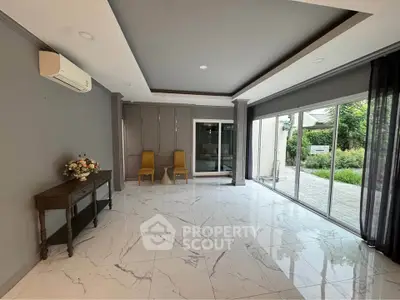 Spacious living room with marble flooring and garden view, featuring elegant decor and large windows.