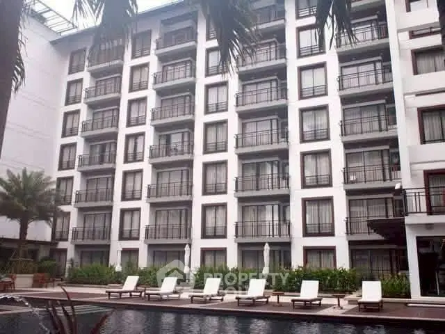 Luxurious apartment building with poolside view and elegant balconies.