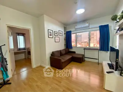 Modern living room with wooden flooring, brown sofa, and city view window in a cozy apartment.