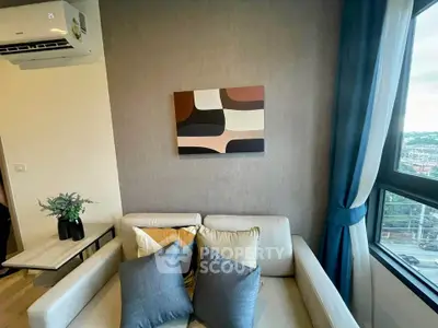 Modern living room with stylish decor and large window offering city views.