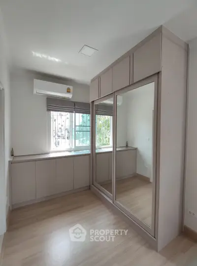 Spacious bedroom with large mirrored wardrobe and natural light