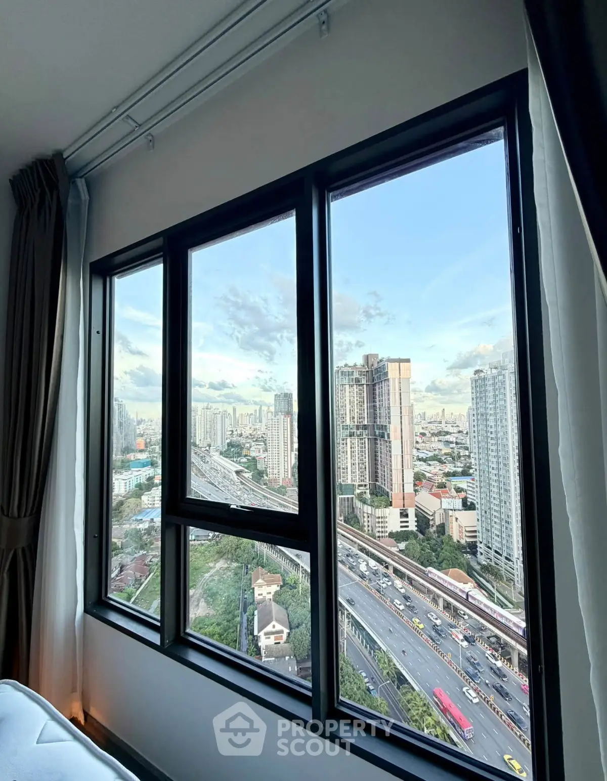 Stunning cityscape view from high-rise apartment window, showcasing urban skyline and bustling streets.