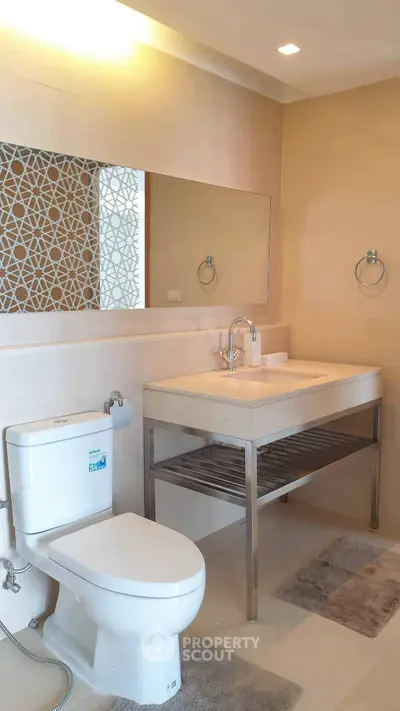 Modern bathroom with elegant sink and toilet, featuring stylish wall design.
