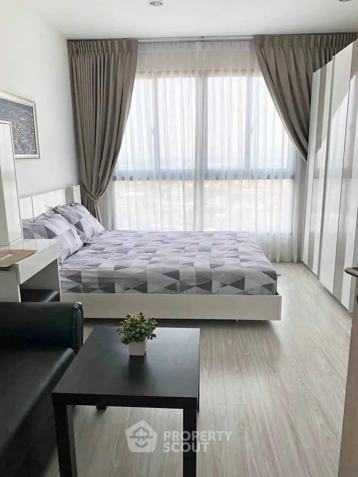 Modern bedroom with large window, stylish decor, and ample natural light in a contemporary apartment.