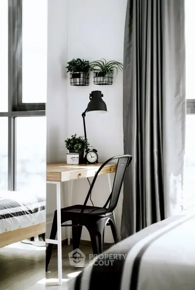 Modern bedroom with stylish desk, chair, and plants by large window.