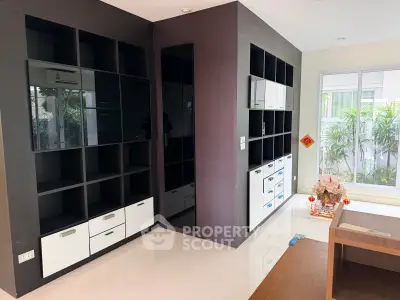 Modern living room with sleek built-in shelving and large windows overlooking greenery.