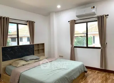 Spacious bedroom with modern decor and large windows offering natural light.