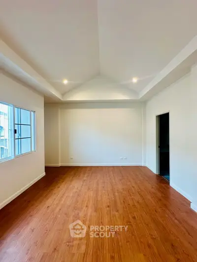 Spacious empty room with wooden flooring and recessed lighting, perfect for customization.