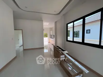 Spacious modern living area with large windows and sleek tile flooring in a new home.