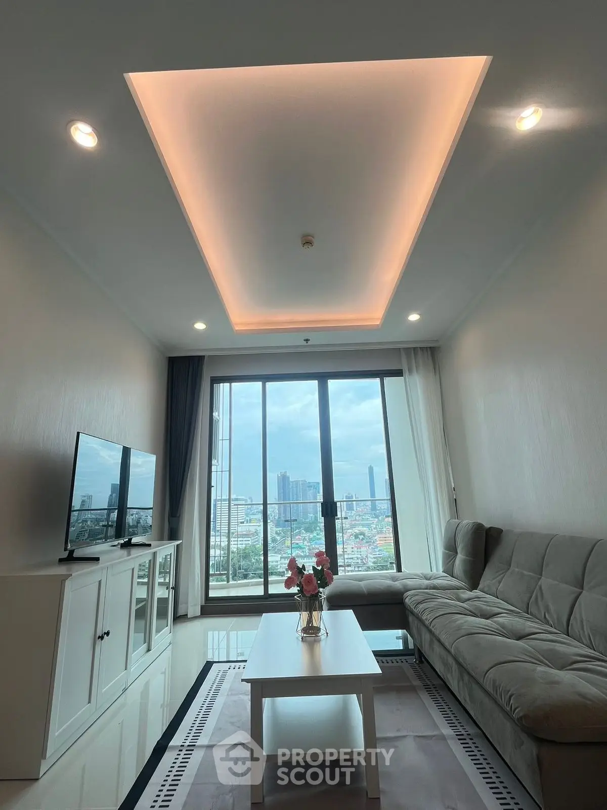 Modern living room with city view, stylish sofa, and sleek TV setup.