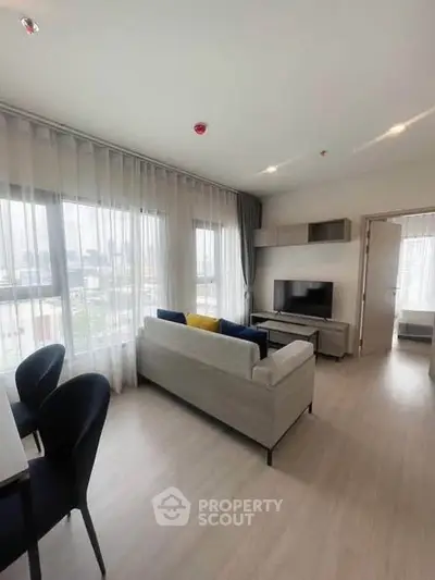 Modern living room with large windows and stylish furniture in a bright apartment.