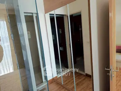 Modern bedroom with mirrored wardrobe and wooden flooring