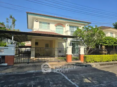 Charming two-story house with gated entrance and lush greenery in a serene neighborhood.