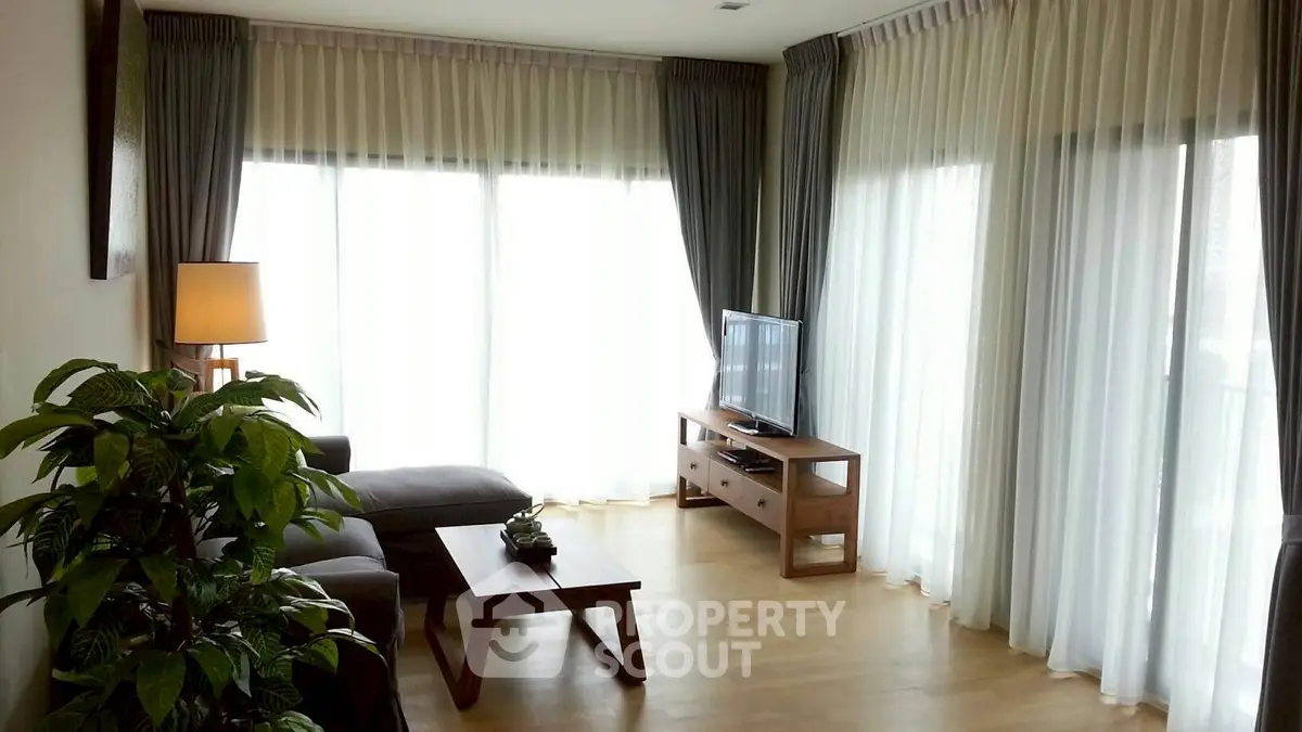 Elegant living room with large windows, sheer curtains, and modern furniture.