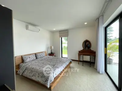 Spacious bedroom with modern decor and large window overlooking greenery, perfect for relaxation.
