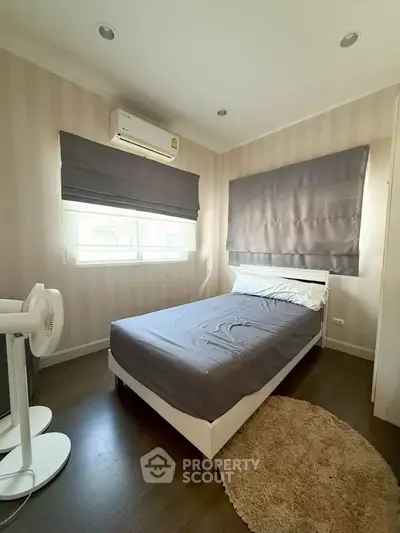 Cozy bedroom with modern decor, featuring air conditioning and natural light.