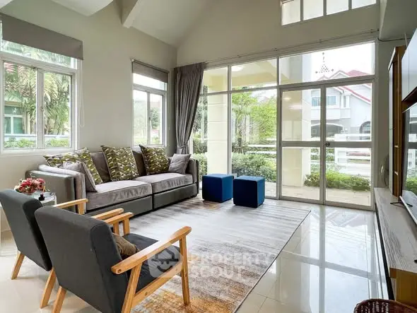 Spacious living room with modern decor and large windows offering garden views.
