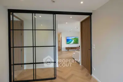 Modern living room with sleek design and large TV, featuring elegant wooden flooring.