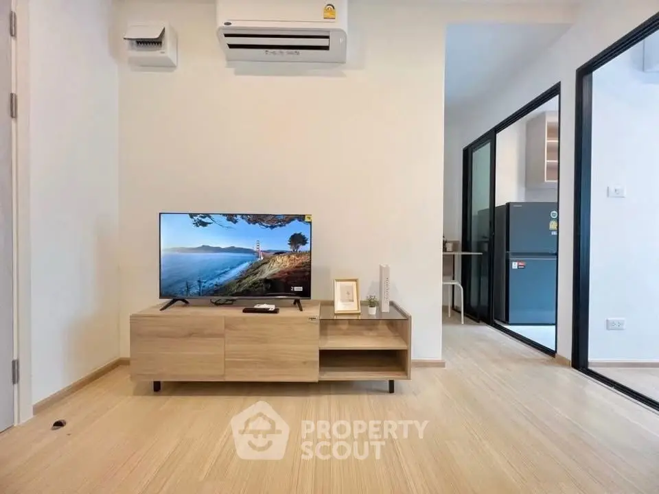 Modern living room with sleek TV unit and view into contemporary kitchen