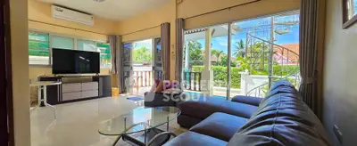 Spacious living room with modern furniture and large windows opening to a lush garden view.