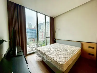 Modern bedroom with large window and city view, featuring a minimalist design and natural light.
