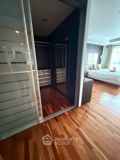 Spacious bedroom with elegant wooden flooring and walk-in closet