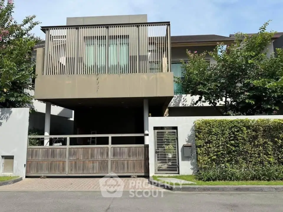 Modern luxury house exterior with gated entrance and lush greenery
