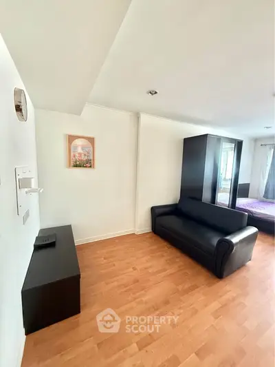 Modern living room with sleek black sofa and wooden flooring