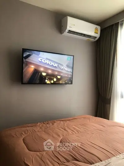 Cozy bedroom with wall-mounted TV and air conditioning unit