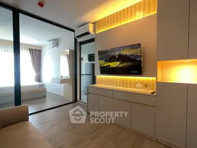 Modern living room with stylish lighting and open view to bedroom, featuring sleek furniture and wooden flooring.