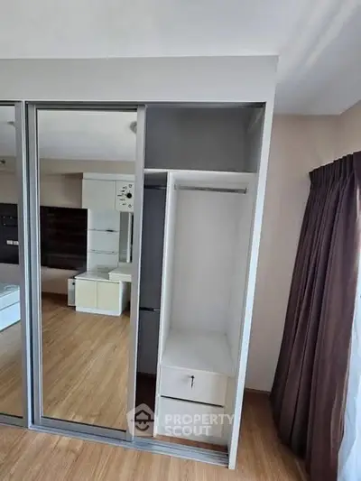 Modern bedroom with mirrored wardrobe and wooden flooring