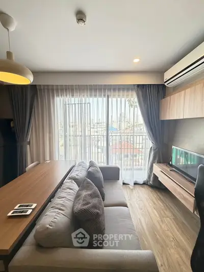 Modern living room with large window and stylish furniture, offering a cozy and bright atmosphere.