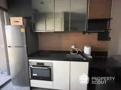 Modern kitchen with sleek cabinetry and built-in oven in a stylish apartment.