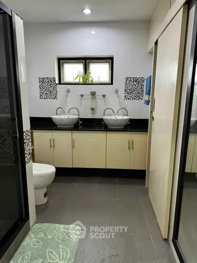 Modern bathroom with dual sinks and stylish black and white tile accents.