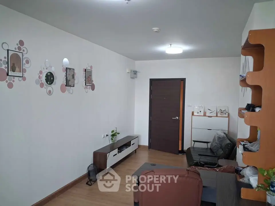 Modern living room with stylish decor and wooden flooring, featuring a cozy seating area and contemporary wall art.