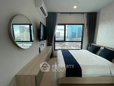 Modern bedroom with city view, featuring sleek furniture and large windows for natural light.