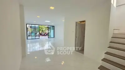 Spacious modern living room with large windows and sleek staircase
