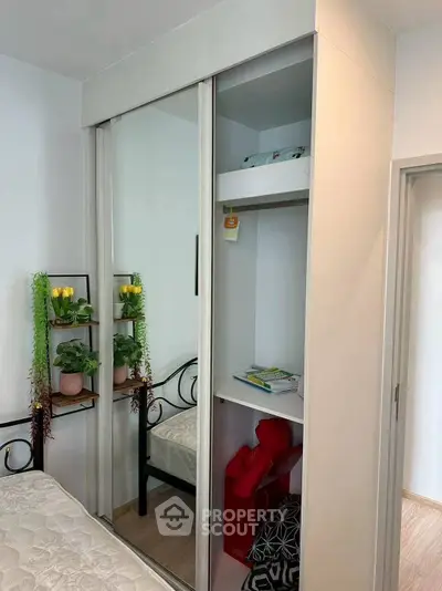 Cozy bedroom with mirrored wardrobe and indoor plants for a refreshing ambiance.